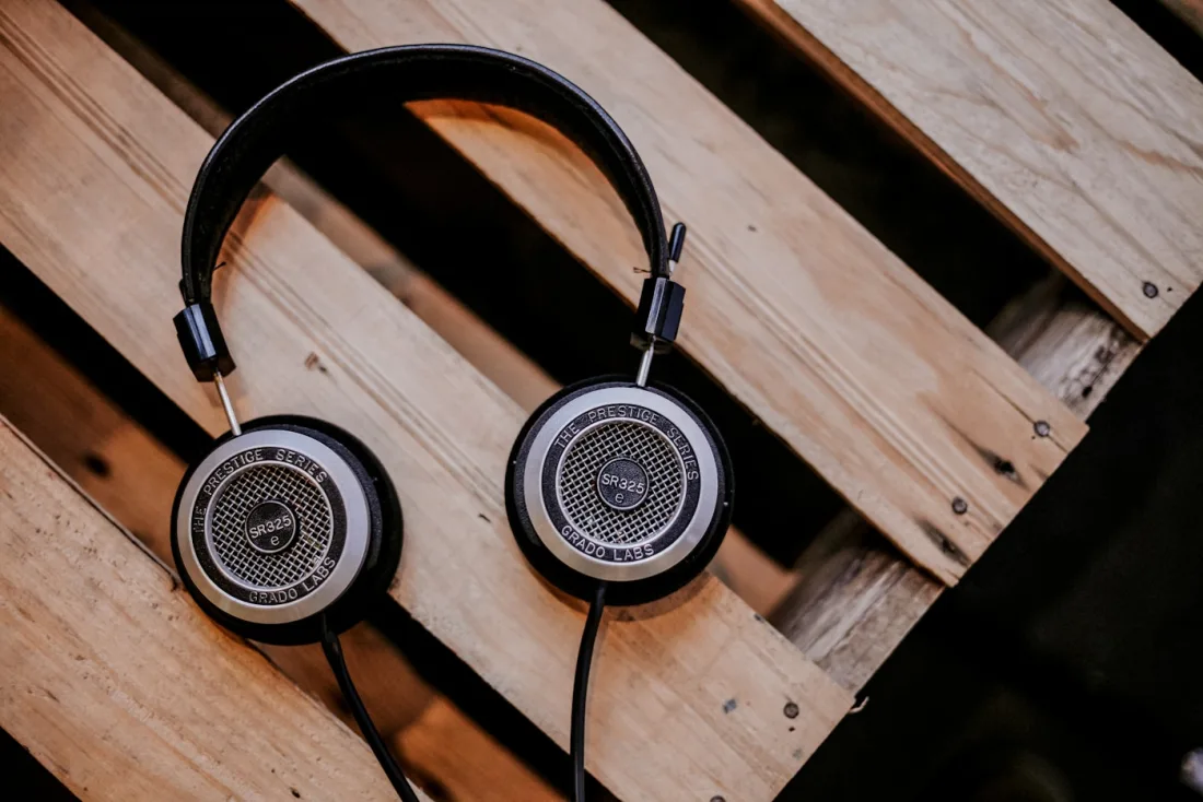 Over-ear headphones resting on a wooden desk, illustrating the equipment needed to listen to 40 Hz gamma audio